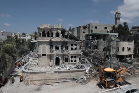 A bulldozer on the corner of a destroyed three-story building