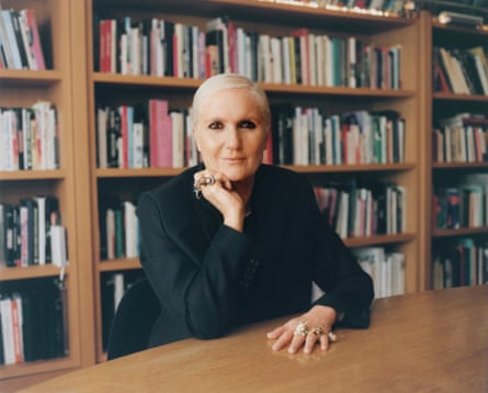 Maria Grazia Chiuri, head of Fendi, sits at a table with a bookcase behind her.