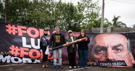 Four people stand in front of a banner featuring Jair Bolsonaro with the word “CENSURADO” across his mouth.