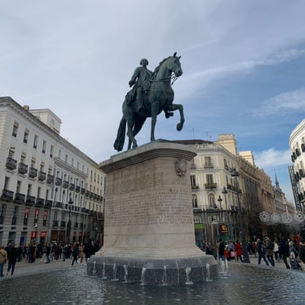 Statue of a man on a horse on top of a plinth surrounded by multi-storey buildings