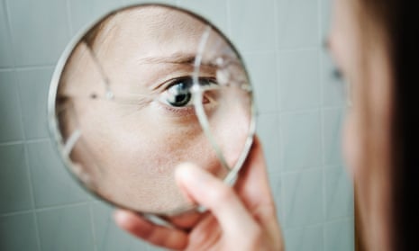 Woman looking at broken mirror