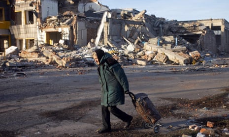 A woman pulls a trolley bag past a destroyed building in Bakhmut.