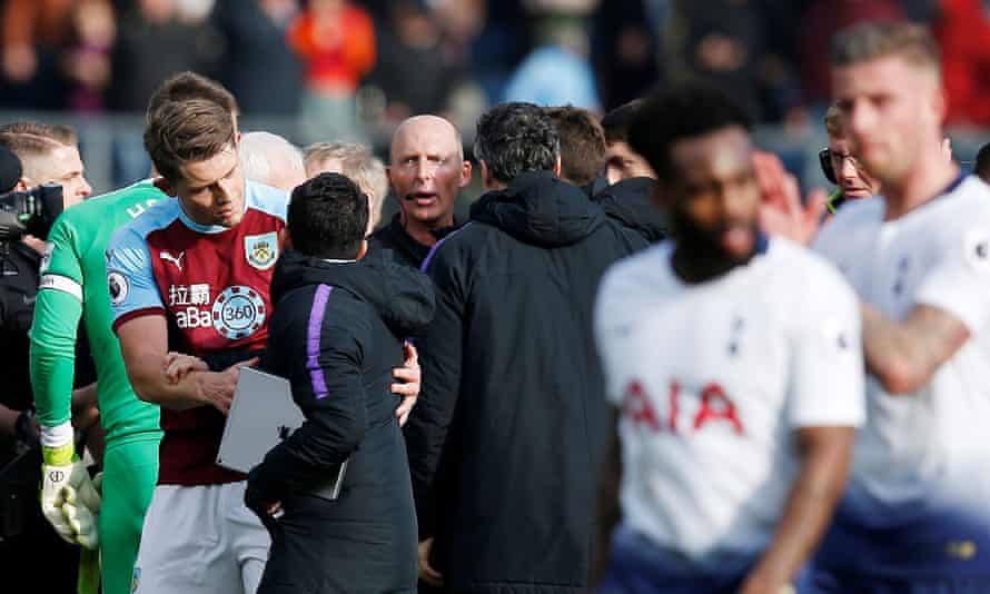 Mike Dean is surrounded by Tottenham’s coaching staff after the final whistle.