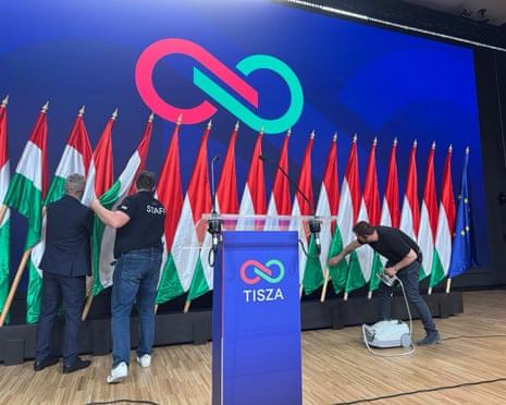 Tisza staff put final touches to Hungary and EU flags behind the podium at which the party leader and presumed next prime minister of Hungary, Peter Magyar, is about to address international media.