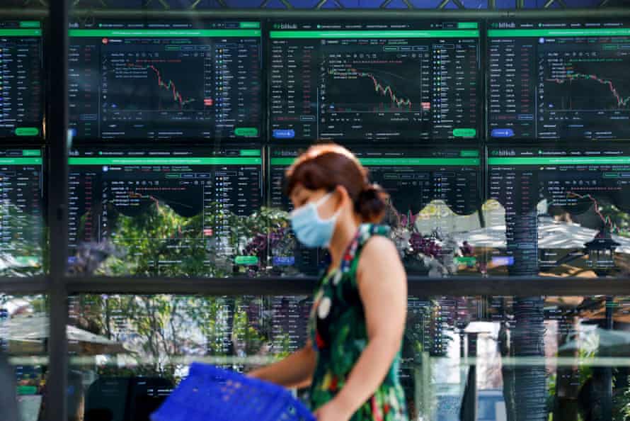 Screens showing cryptocurrency trends and prices at a cafe in Thailand.