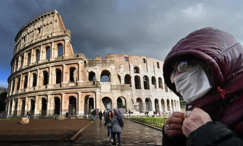 A man wearing a protective mask passes by the Coliseum in Rome.