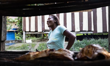A woman is seen by a stall behind some smoked fish