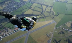 Skydiver free falling above countryside seconds before deploying parachute