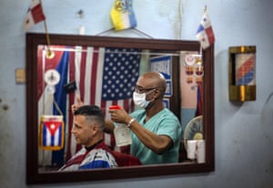 Barber Eugenio Lafargue styles a customer’s hair in Havana