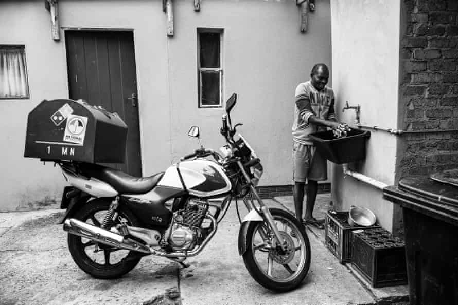 Ghost riders: the invisible lives of Johannesburg food couriers – photo essay | South Africa 8 Mukisa washes dishes outside his room