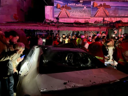 People gather around a bombed car next to a cafe late at night