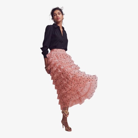 A midel wears the pink and black polka dot Boden Tulle Tiered Skirt, with a long sleeve black top and strappy heels.
