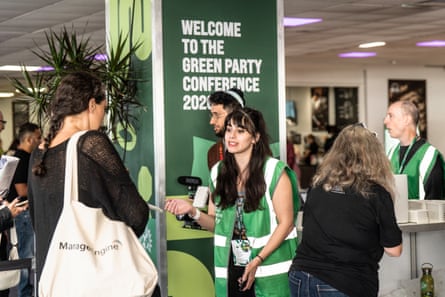 People in green hi-vis tops help people check-in to a conference venue