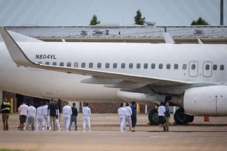 a group of people stand in a row on tarmac outside plane