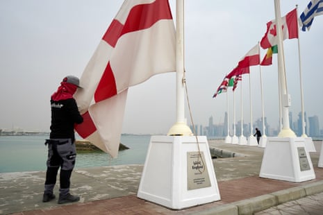 A worker on Doha’s Corniche promenade trims the frayed edges of flags representing the 32 countries that will compete in the 2022 World Cup in Qatar