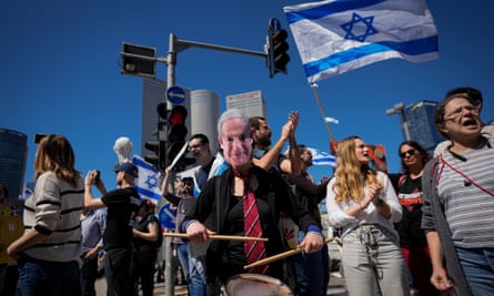 A demonstrator wears a mask depicting Benjamin Netanyahu during a protest in Tel Aviv.