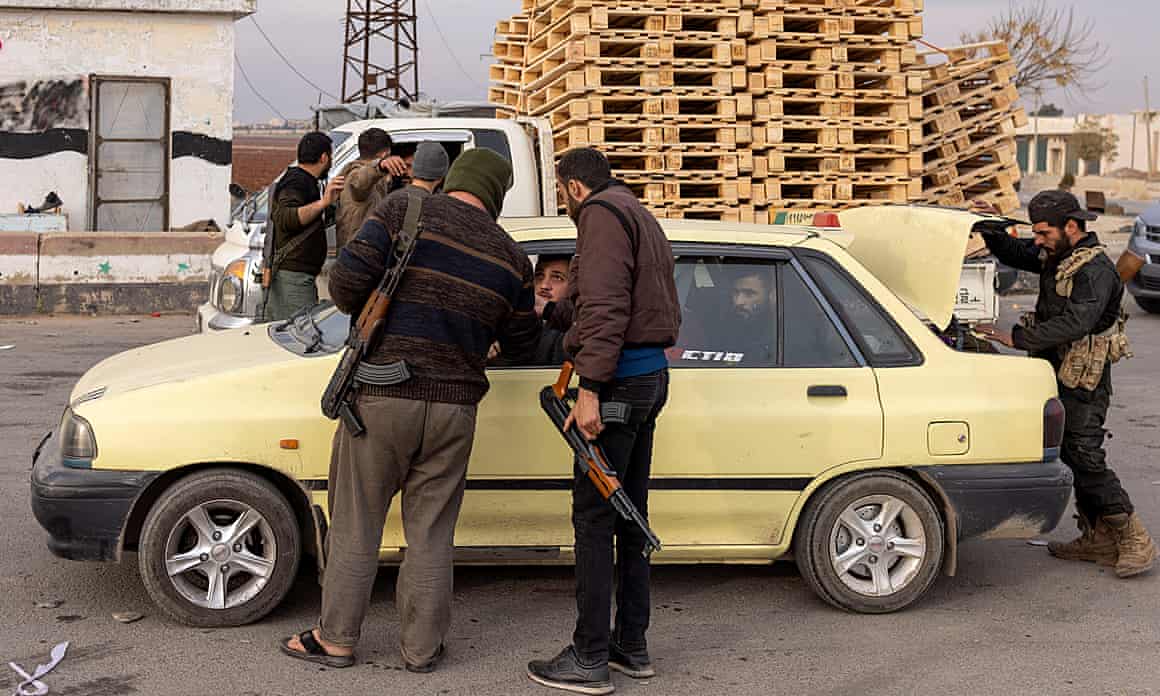 Fighters of Hayat Tahrir al-Sham search a car in rural Aleppo