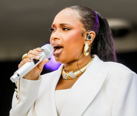 Woman in white suit sings.