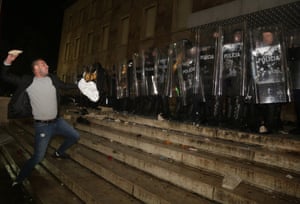 A protester throws a stone at police officers outside the prime’s minister office during clashes in Tirana. Hundreds are demanding the interior minister’s resignation over the fatal police shooting of a 25-year-old man who had breached a coronavirus-linked curfew.