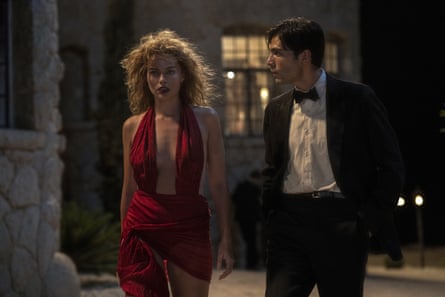 Robbie in a red dress and Calva in a tuxedo walk together at night