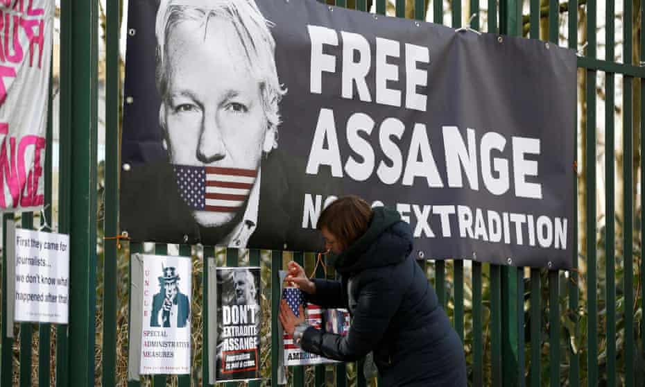 A Julian Assange supporter attaches a sign to a fence outside Woolwich crown court in London.
