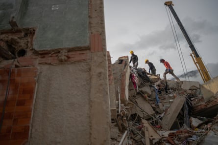 Silvio Sivira, Eduardo Perozo and Edwin Rodriguez, volunteers from Poblado Uno, walk over the rubble of the Costa Brava building on 3 July 2026