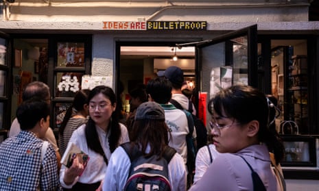 People queue outside a bookshop with a sign over the doorway saying 'Ideas are bulletproof’
