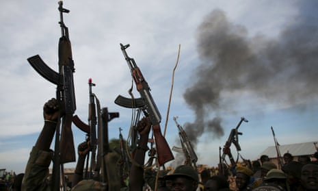 Rebel fighters hold up their rifles as they walk in front of a bushfire in Upper Nile State, South Sudan, in February 2014. The civil war is now entering its third year.