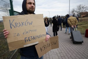 A Ukrainian man living in Kraków holds a sign offering free transportation for people who arrive at the border crossing in Medyka, Poland