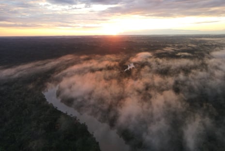 Aerial view of mist over a bend in a river as the sun rises