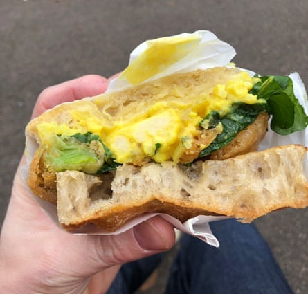 sandwich with a bright yellow filling, and green leaves and some leek fritters