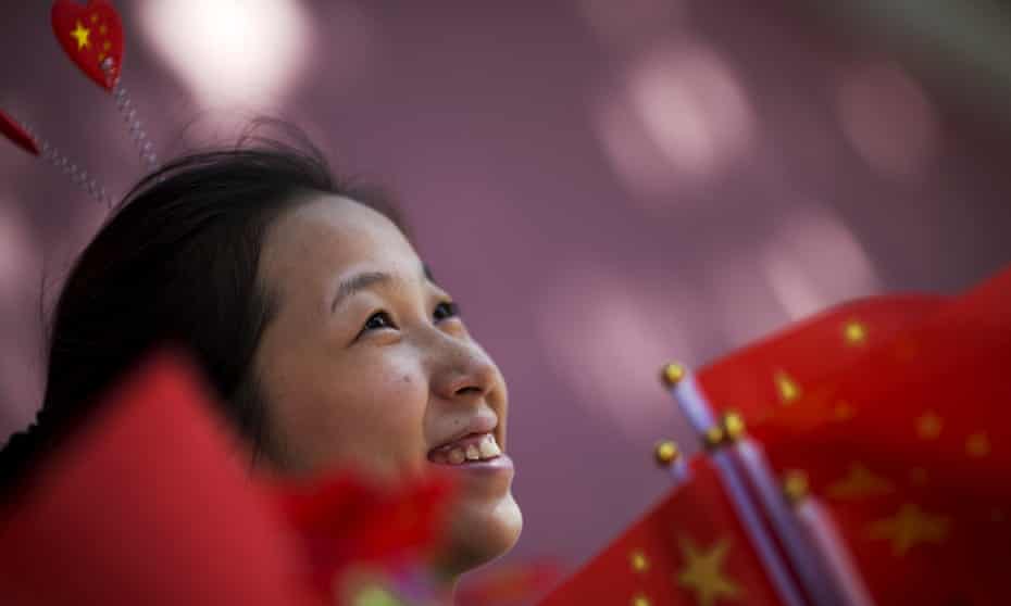 A young woman in Beijing offers flags, stickers and hairpins in national colours to people gathering near Tiananmen Gate to celebrate national day.