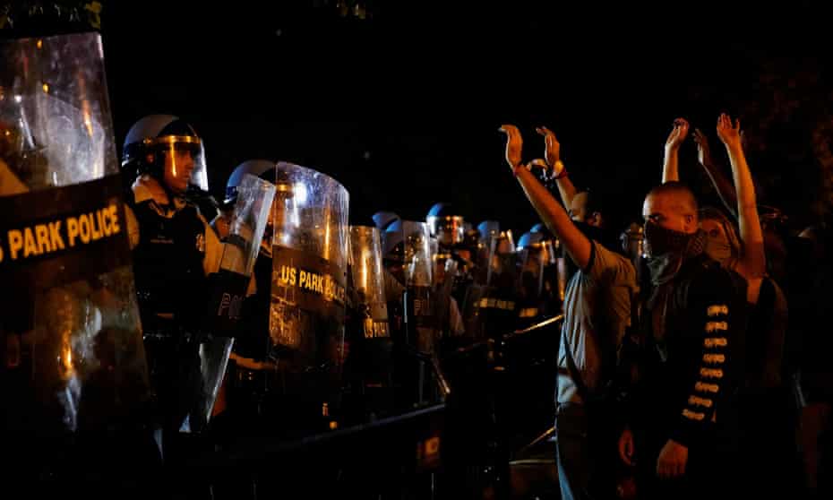 US park police in riot gear look on as people protest near the White House against the death of George Floyd, 30 May 2020.