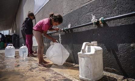 A girl fills a large water bottle using a tap