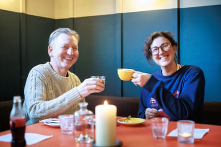 A man and woman toasting each other at a restaurant table