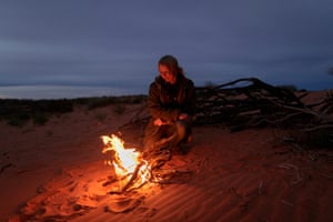 Sophie Matterson warms herself by the fire after setting up camp.