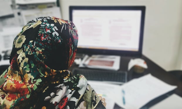 A woman wearing a hijab using a computer