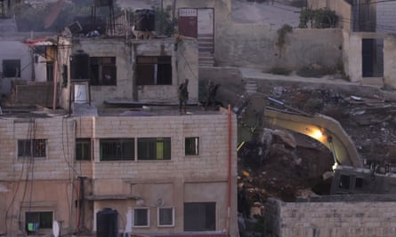 Israeli soldiers throw the body of a Palestinian man off a roof during a raid in Qabatiya.