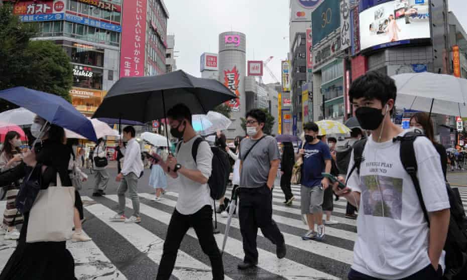Pedestrians wearing protective masks walk a crossway at Shibuya in Tokyo