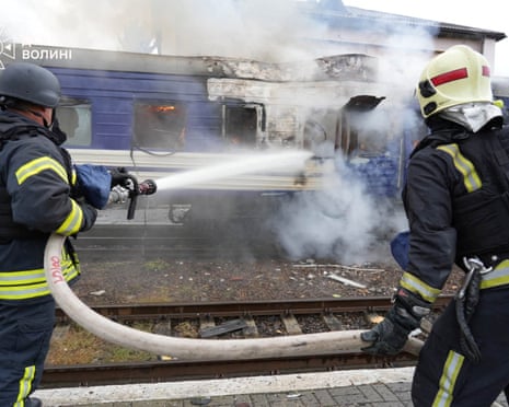 Firefighters spray water at a burning train carriage hit