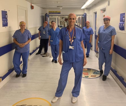 Six nurses wearing their uniform stand in a hospital hallway