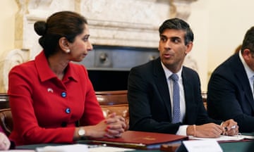 Suella Braverman in red coat looks at Rishi Sunak as he speaks to her during a roundtable meeting