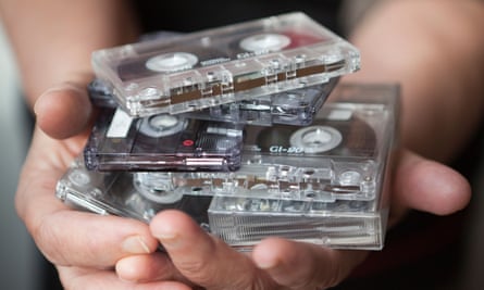 two hands holding a stack of audio cassette tapes