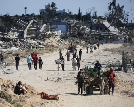 Displaced Palestinians walk past destroyed buildings as they return to their homes in the in al-Zahra area, north of the Nuseirat refugee camp in central Gaza
