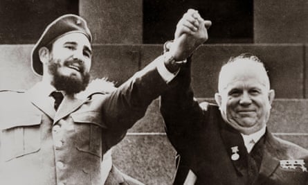 A black-and-white image of two smiling men holding their clasped hands above and between them. Younger, bearded man in beret on left, older man on right.