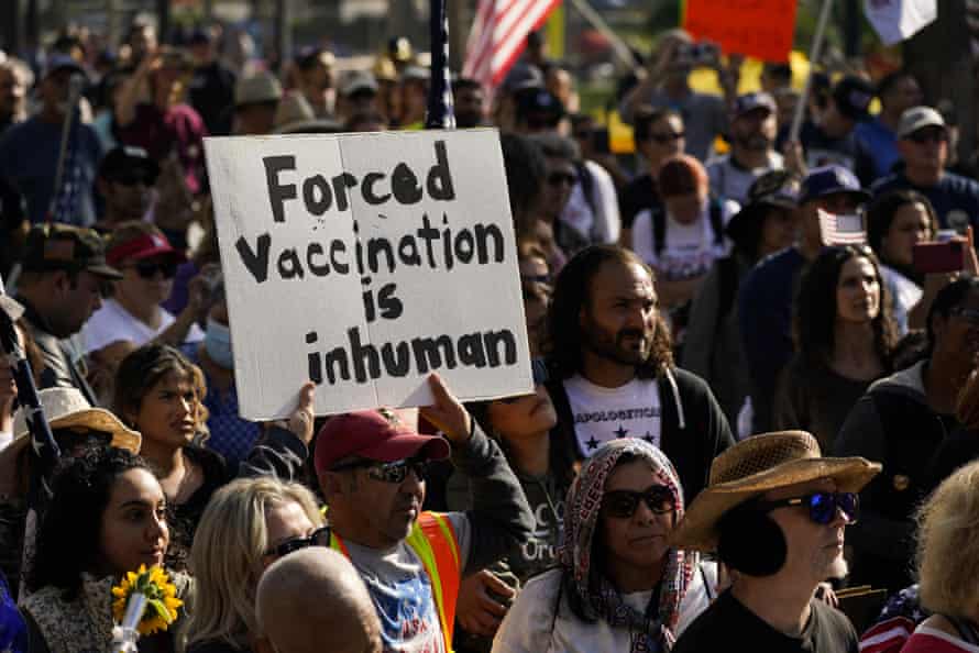 A man holds a sign that says "Forced vaccination is inhuman" while listening to a speaker at a rally to protest the city’s new vaccine mandate.