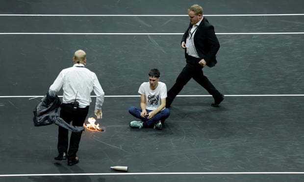 A protester against private jets sets fire to his arm on court at the O2 Arena.