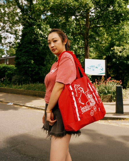 A side view of a woman wearing an Arsenal top and carrying a red tote bag.