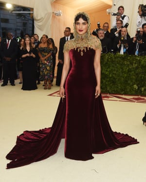 The simplicity of Priyanka Chopra's deep burgundy strapless Ralph Lauren gown offset the drama of her elaborate gold jewelled hood.