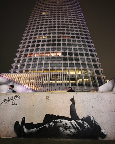 A black and white mural of two children lying on their backs, one of them pointing upwards, with the Centrepoint building in the background